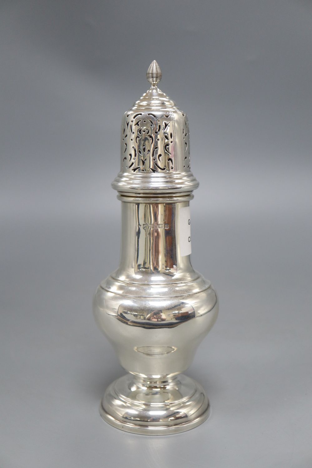 A silver vase shape sugar shaker, with pierced domed cover, ribbed finial on circular base, Birmingham 1932, 7.6oz., height 23cm